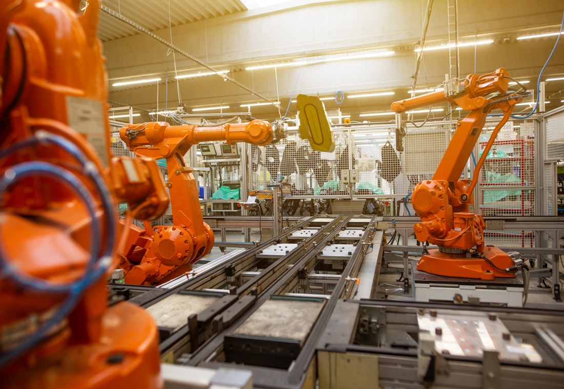 Fabrikada turuncu robot kollarla çalışan üretim hattı